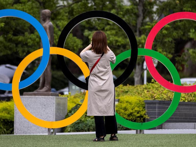 Eine Frau fotografiert die Olympischen Ringe in Tokio.