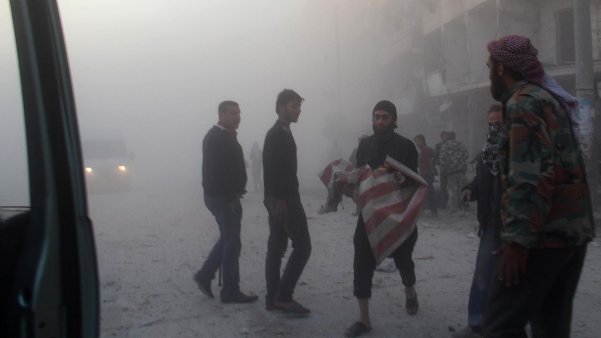Ein Syrer rettet einen scheinbar leblosen Körper aus einem Haus nach einem Fassbomben-Angriff durch die syrische Armee in Aleppo.