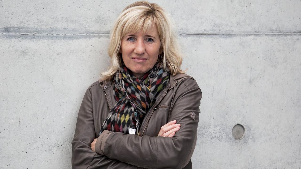 Die Schriftstellerin und Doping-Expertin Ines Geipel, die Arme verschränkt, an eine graue Betonmauer gelehnt. Die Schriftstellerin und Doping-Expertin Ines Geipel, die Arme verschränkt, an eine graue Betonmauer gelehnt.
