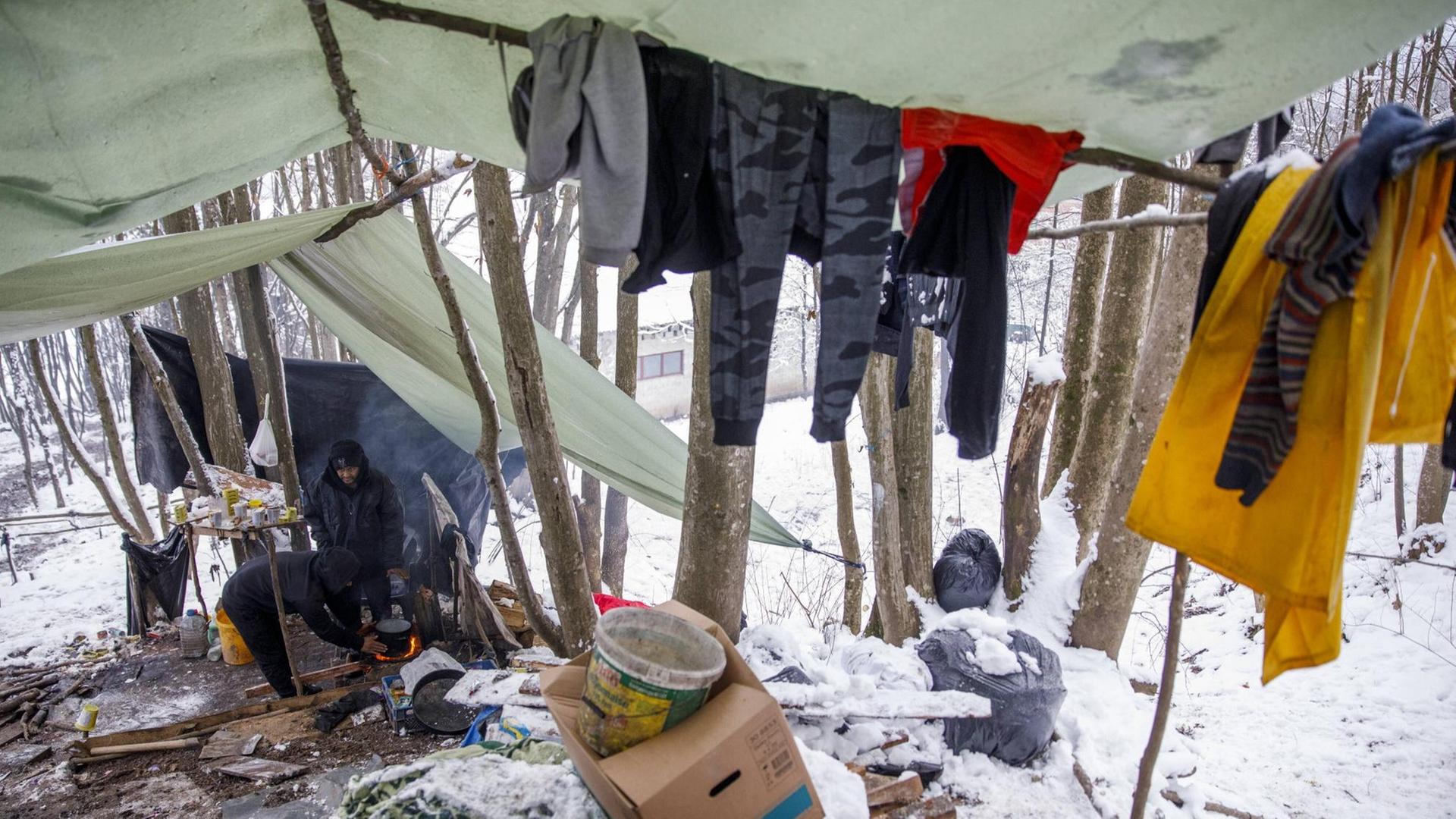 Zwei Flüchtlinge unter selbstgebauten Zeltplanen in einem verschneiten Wald Zwei Flüchtlinge unter selbstgebauten Zeltplanen in einem verschneiten Wald