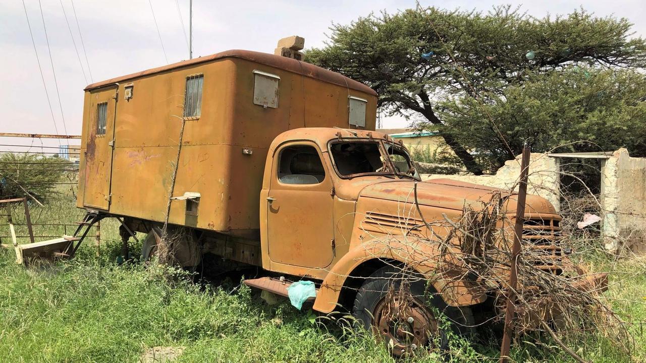 Ein alter gelber, alter, angerosteter LKW steht auf einem wilden Stück Land. Das Fahrerhaus hat keine Scheiben mehr. Ein alter gelber, alter, angerosteter LKW steht auf einem wilden Stück Land. Das Fahrerhaus hat keine Scheiben mehr.