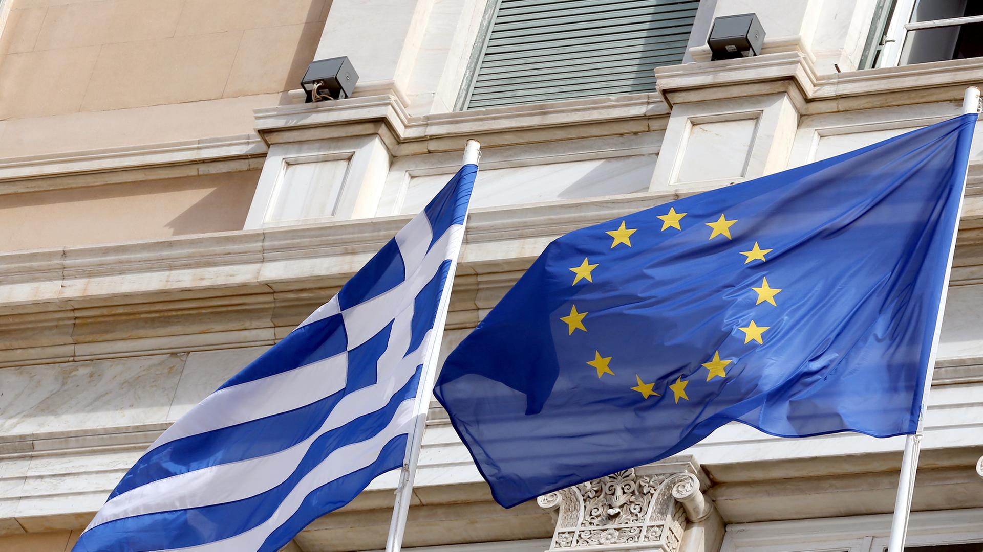 Die griechische und die europäische Flagge wehen am 06.03.2014 vor dem Parlamentsgebäude in Athen. Foto: Wolfgang Kumm/dpa