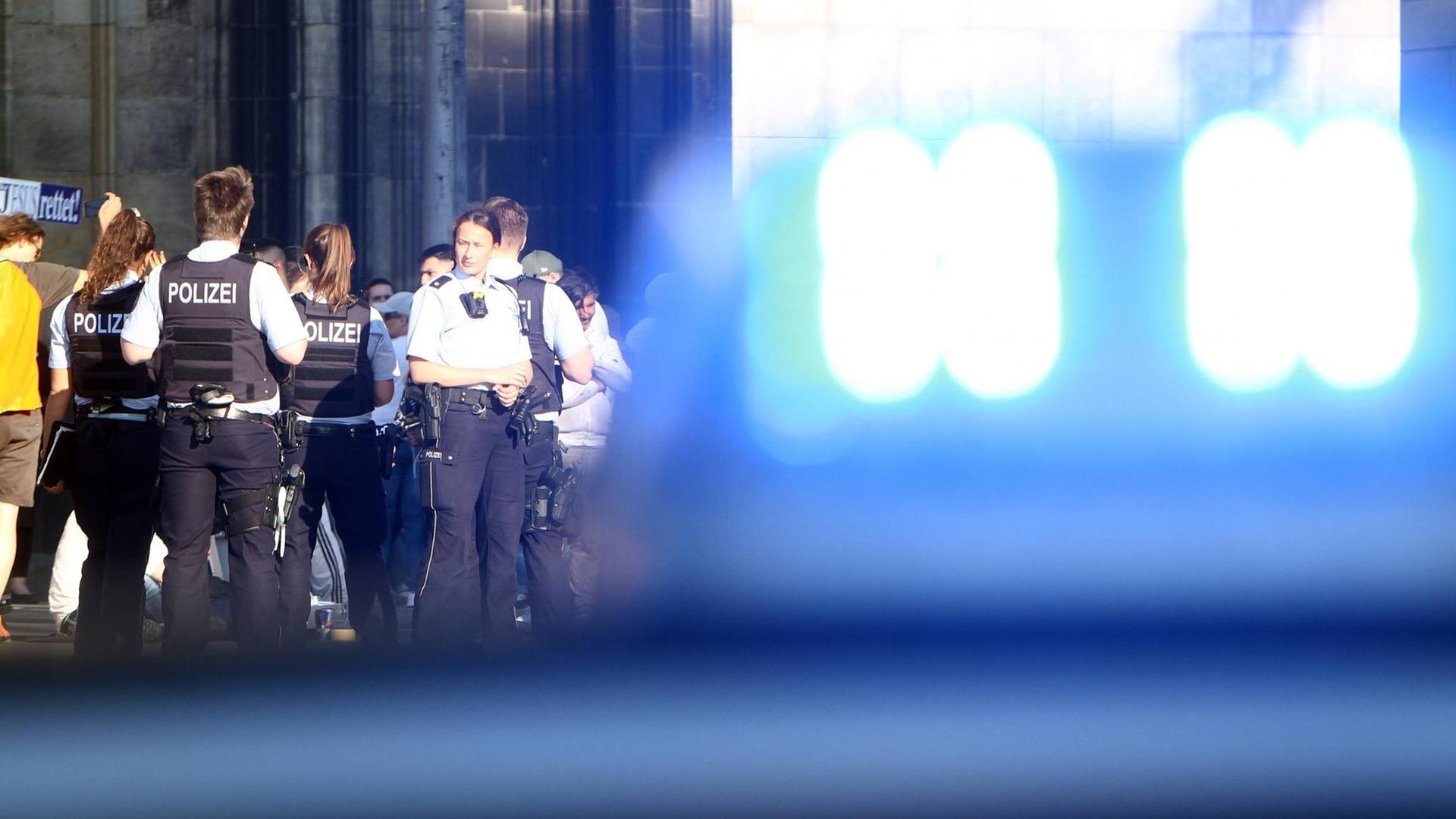 Einsatzwagen der Polizei mit Blaulicht und Polizeibeamte bei einem Einsatz auf der Domplatte am Kölner Dom, Köln