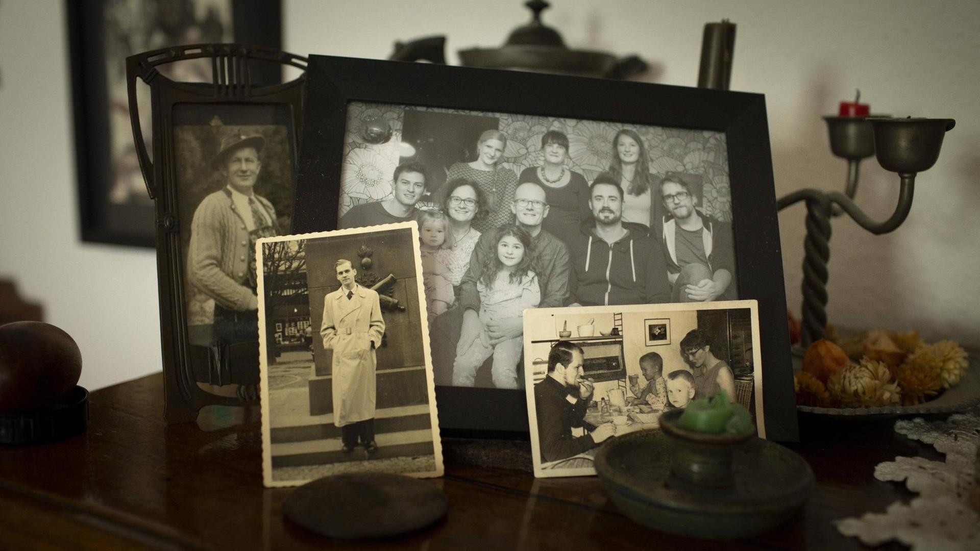 Auf einer Anrichte sind verschiedene schwarzweiß Fotografien von einzelnen Menschen und Familien zu sehen. Auf einer Anrichte sind verschiedene schwarzweiß Fotografien von einzelnen Menschen und Familien zu sehen.
