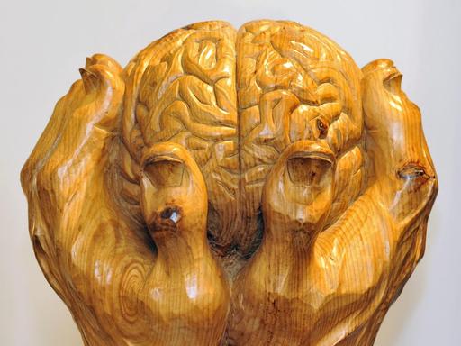 Zu sehen ist eine Skulptur des Künstlers Loris Marazzi. Zwei Hände halten ein Gehirn.