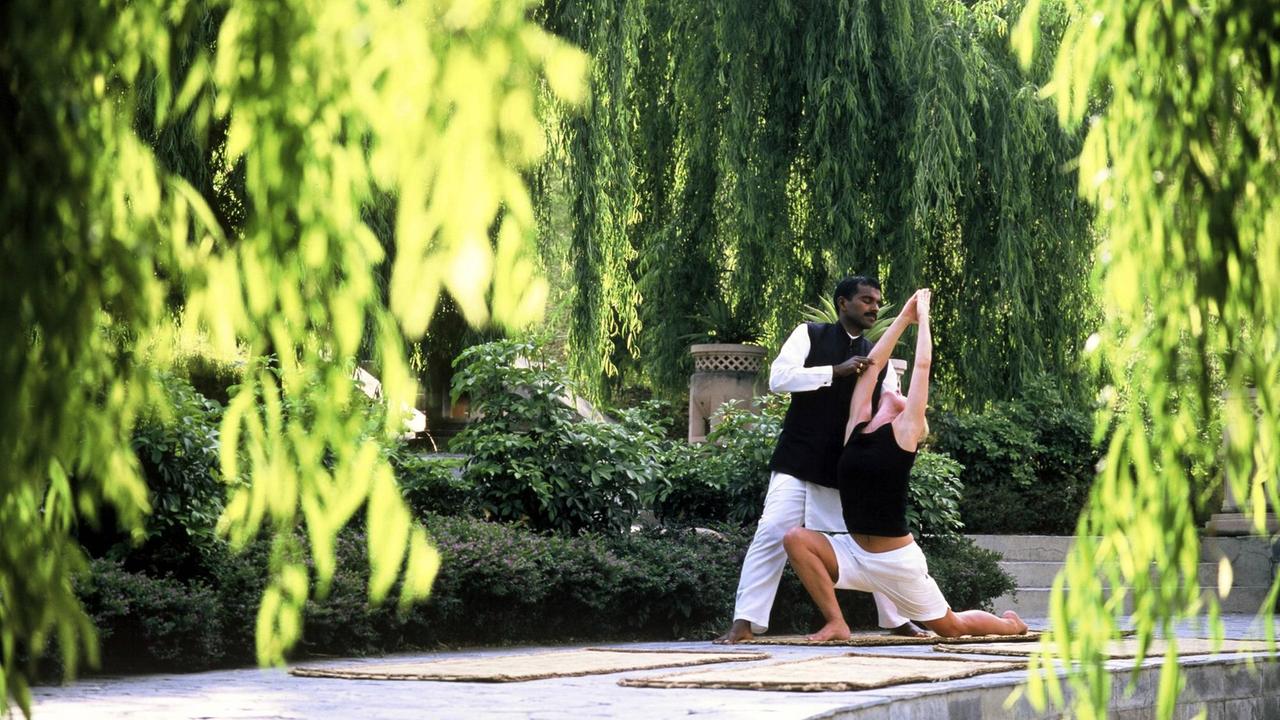 Ein indischer Lehrer korrigiert die Yogaübung eines Weißen. Ein indischer Lehrer korrigiert die Yogaübung eines Weißen.