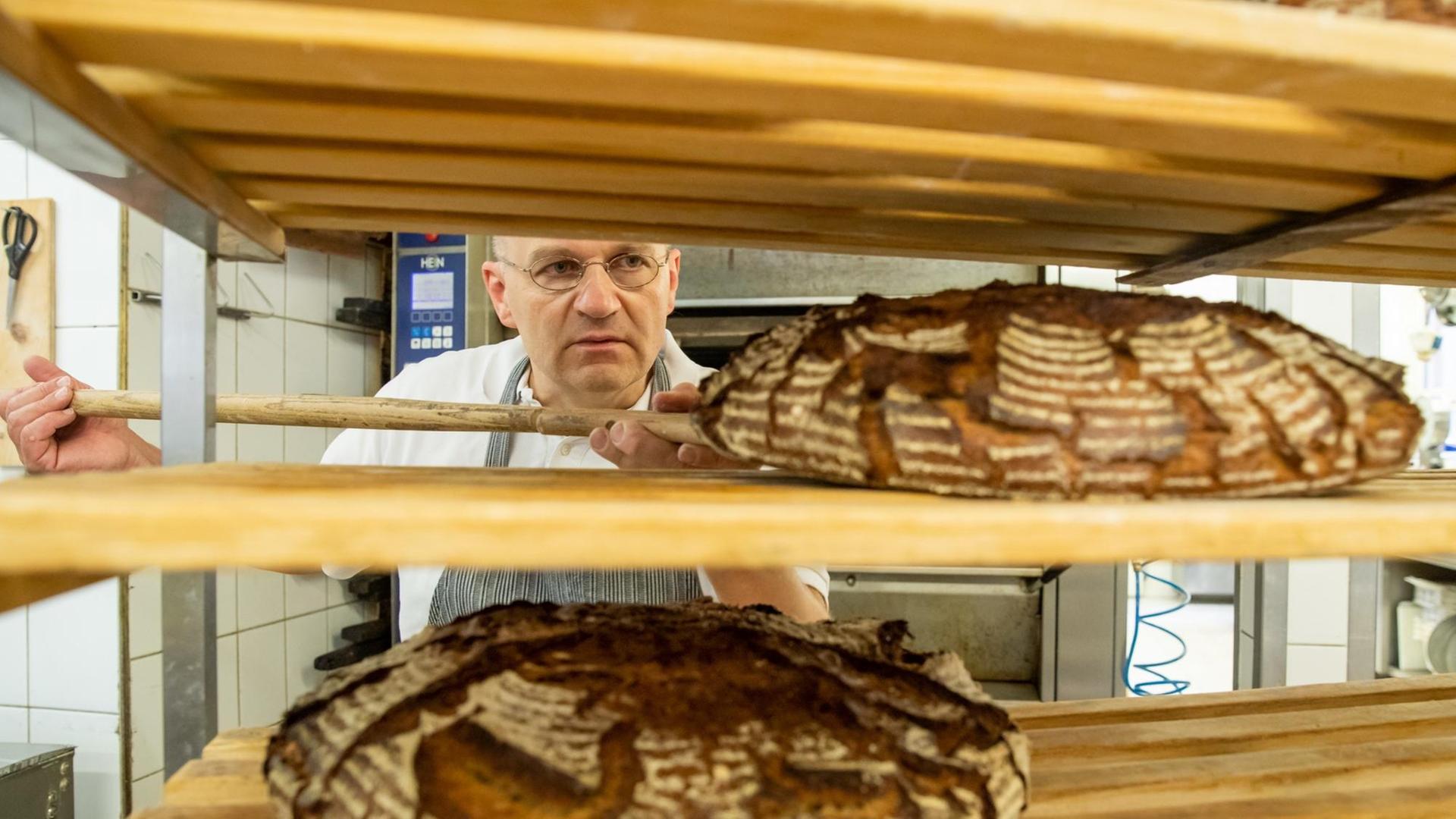 Bäcker Arnd Erbel legt ein Brot in ein Regal. Bäcker Arnd Erbel legt ein Brot in ein Regal.