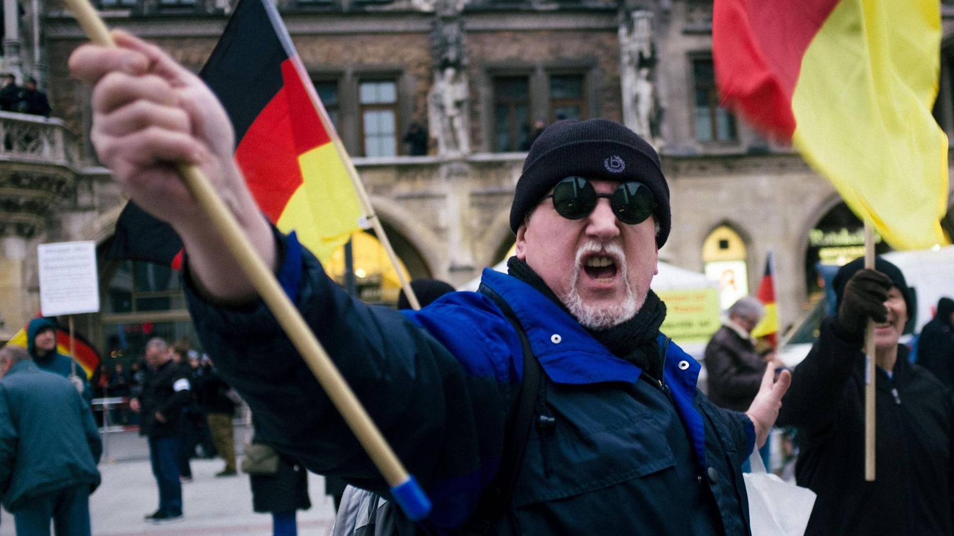 Ein vermummter Pegida-Demonstrant schwenkt eine Deutschland-Fahne. Ein vermummter Pegida-Demonstrant schwenkt eine Deutschland-Fahne.