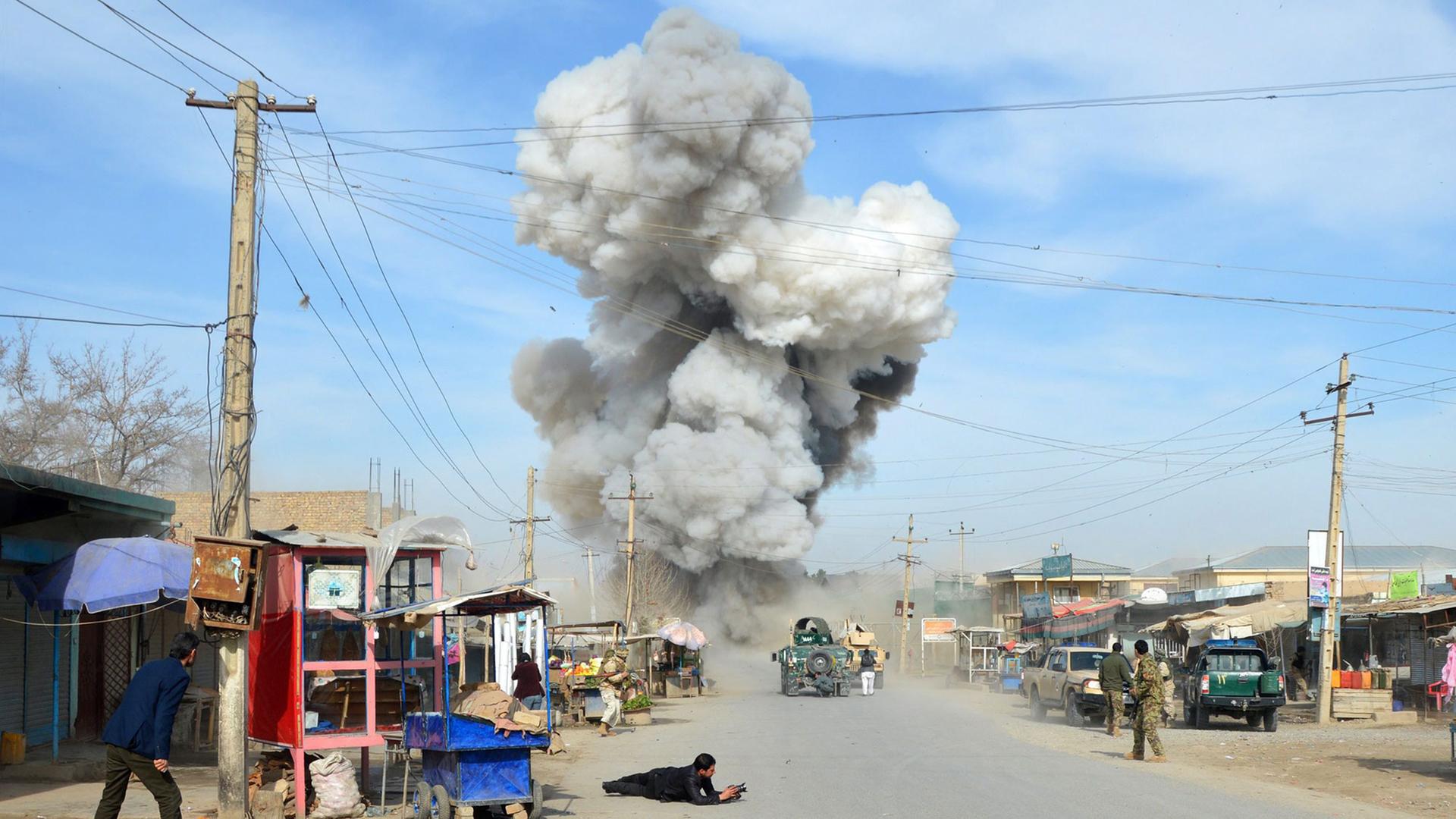 Nach einem Selbstmord-Bombenanschlag durch fünf Talibankämpfer auf ein Polizei-Hauptquartier in Kundus in Afghanistan am 10.02.2015 steigt über einer Straße mit Militärfahrzeugen eine Rauchwolke auf. Nach einem Selbstmord-Bombenanschlag durch fünf Talibankämpfer auf ein Polizei-Hauptquartier in Kundus in Afghanistan am 10.02.2015 steigt über einer Straße mit Militärfahrzeugen eine Rauchwolke auf.
