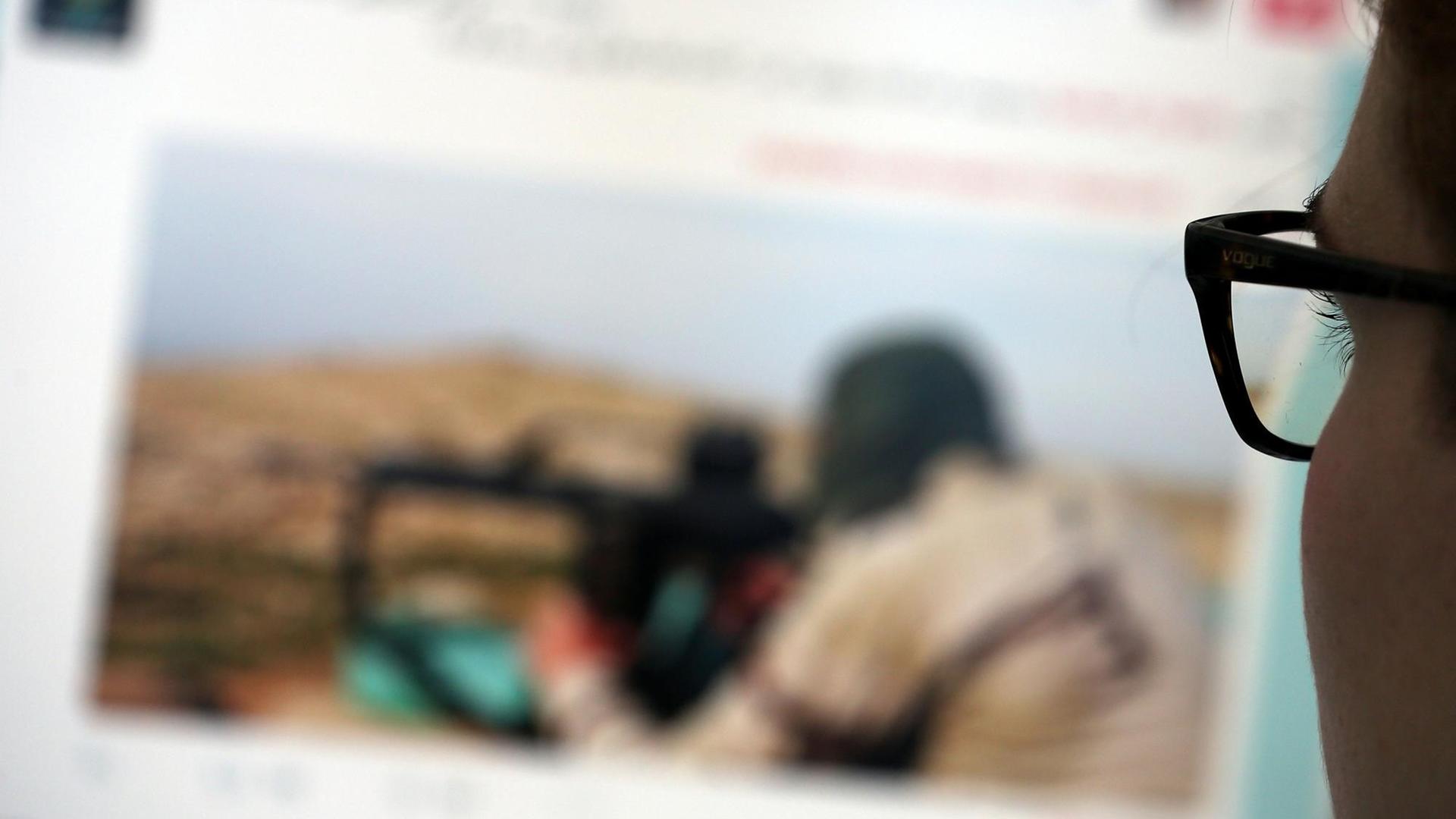 Eine junge Frau schaut auf einen Computermonitor, auf dem einer Website mit Propaganda des IS zu sehen ist. Eine junge Frau schaut auf einen Computermonitor, auf dem einer Website mit Propaganda des IS zu sehen ist.