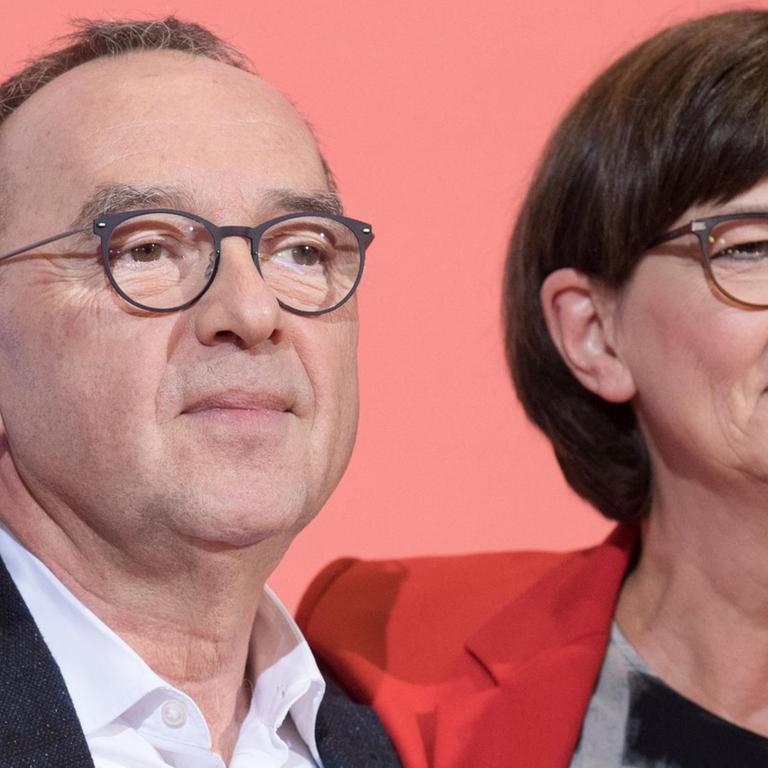 Die SPD-Politiker Norbert Walter-Borjans und Saskia Esken stehen auf einem Podium.