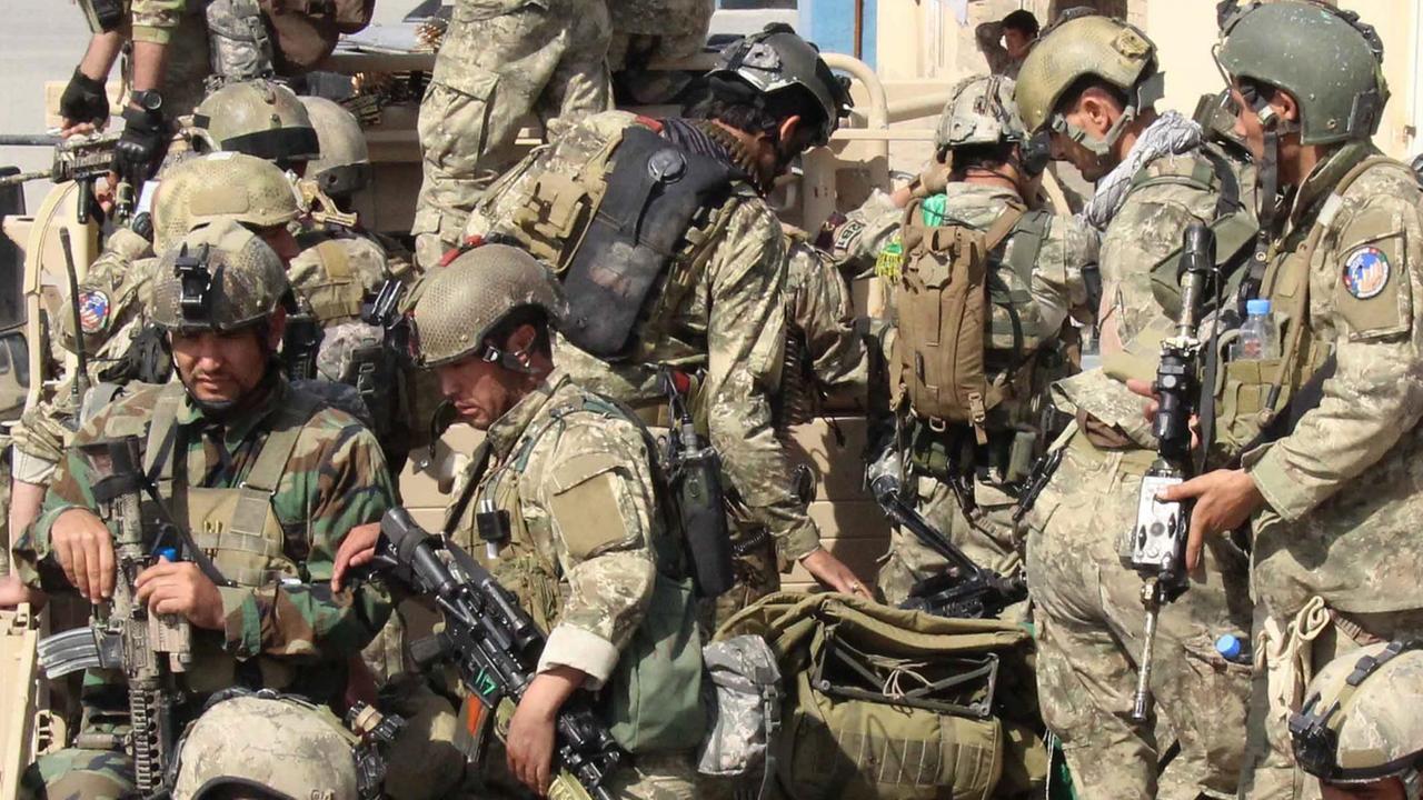 Das Bild zeigt viele schwerbewaffnete Soldaten in Tarnuniformen und Helmen auf bzw. vor der Ladefläche eines Militär-Lastwagens.