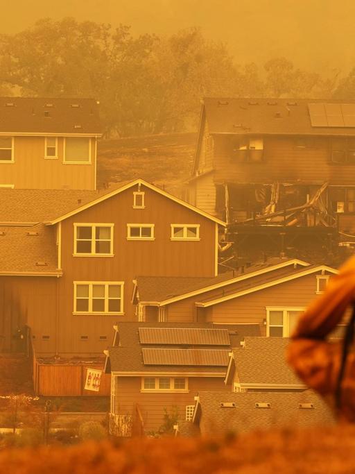 Ein Feuerwehrmann schaut auf ein verbranntes Haus in Kalifornien, USA