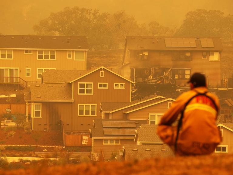 Ein Feuerwehrmann schaut auf ein verbranntes Haus in Kalifornien, USA