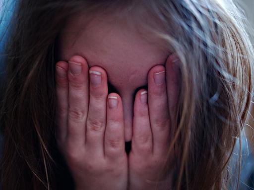ILLUSTRATION - Ein junges Mädchen hält sich am 24.01.2014 in Berlin die Hände vor ihr Gesicht