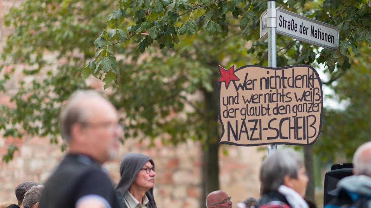 Ein Schild hängt während der Kundgebung der Chemnitzer Friedensgruppen am Roten Turm an einem Straßenschild. Darauf steht: Wer nichts denkt und nichts weiß. der glaubt den ganzen Nazi-Scheiß.