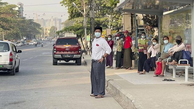 Einige Menschen stehen an einer Bushaltestelle in Rangun