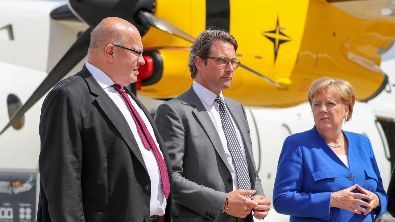 Peter Altmaier (CDU, l-r), Bundesumweltminister, Andreas Scheuer (CSU), Bundesverkehrsminister, und Angela Merkel, Bundeskanzlerin (CDU), stehen vor einer Dornier 328 vor der ersten Nationalen Luftfahrtkonferenz auf dem Flughafen Leipzig-Halle. 