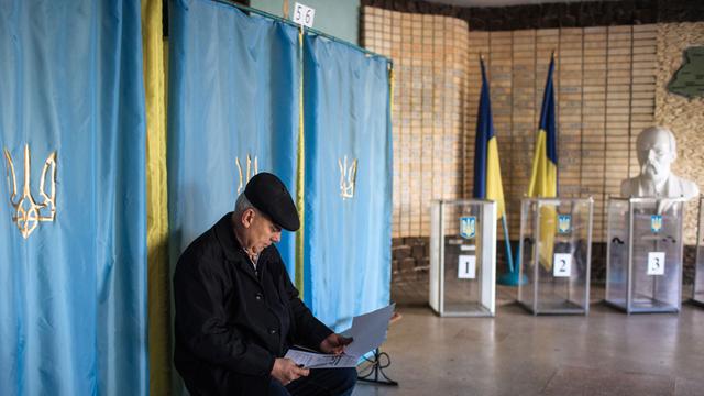 Ein Mann sitzt mit Unterlagen in einem Wahllokal zur Parlamentswahl in der Ukraine in der ostukrainischen Stadt Kramatorsk.