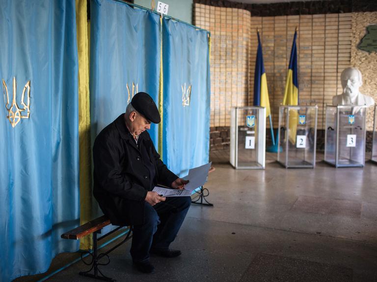 Ein Mann sitzt mit Unterlagen in einem Wahllokal zur Parlamentswahl in der Ukraine in der ostukrainischen Stadt Kramatorsk.