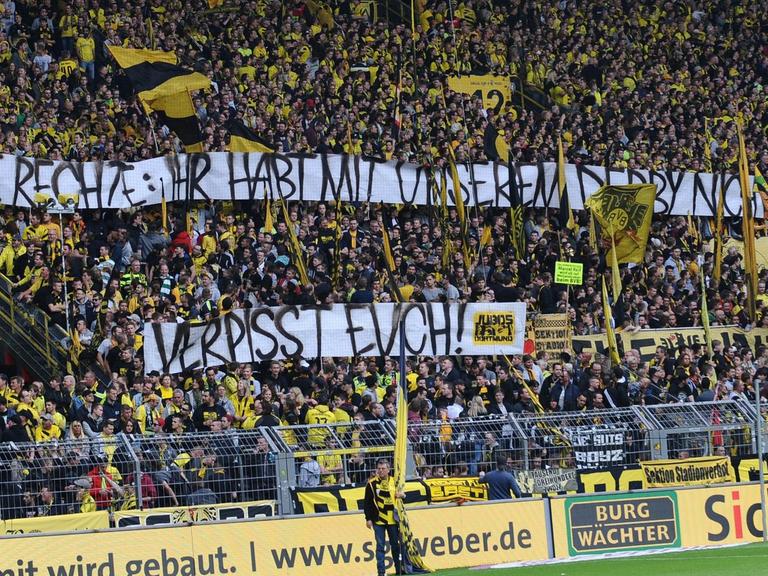 Dortmunds Fans zeigen ein Transparent mit der Aufschrift "@Die Rechte: ihr habt mit unserem Derby nichts zu tun, verpisst Euch". 