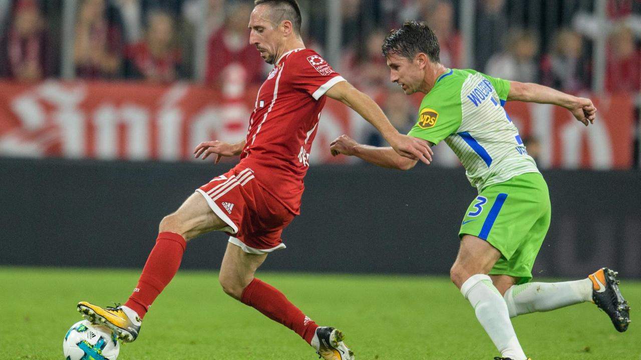 Das Bild zeigt Franck Ribery von Bayern München (l) und Paul Verhaegh vom VfL Wolfsburg im Zweikampf um den Ball.
