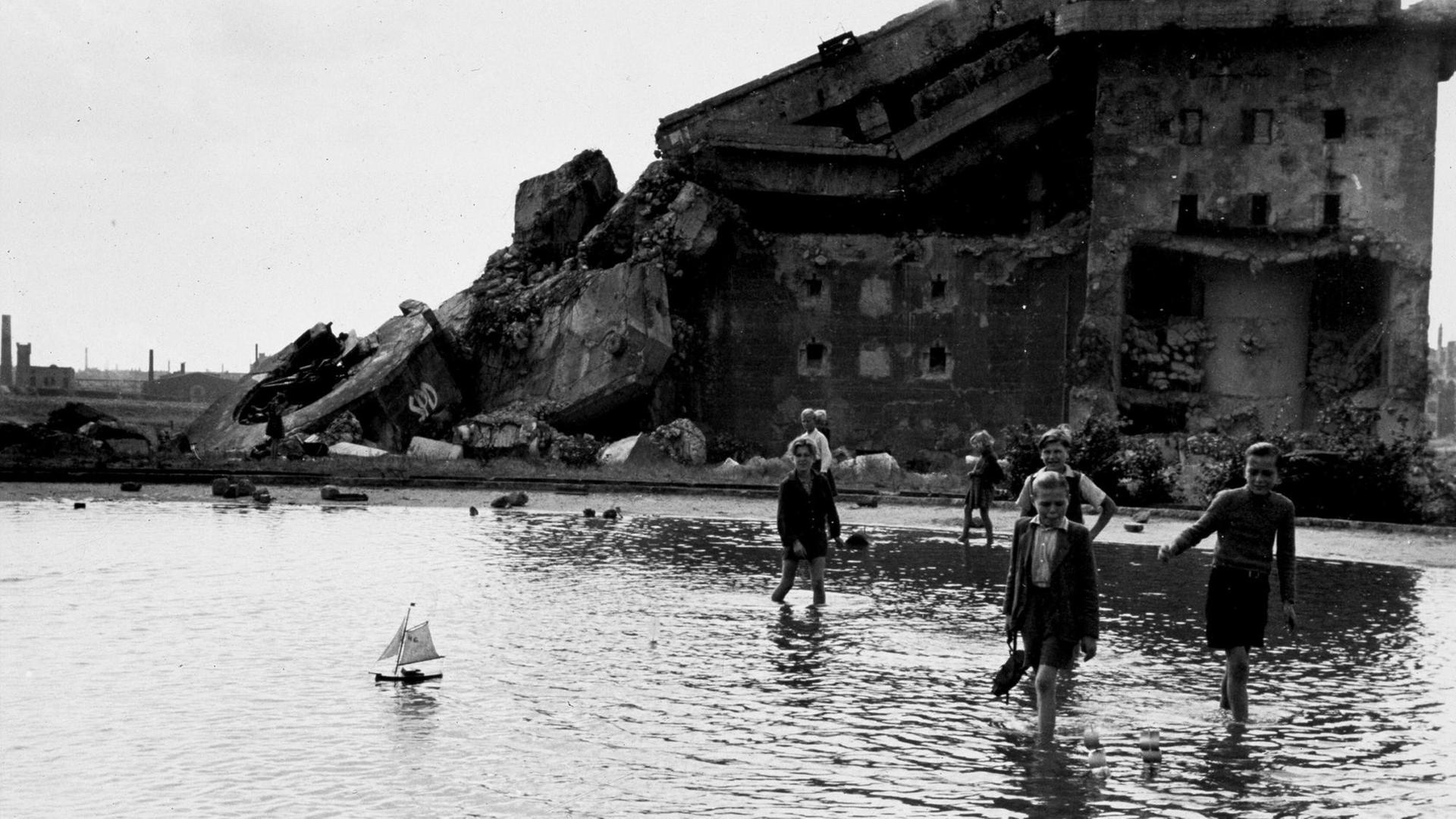 Kinder spielen mit selbstgebastelten Segelschiffchen im Humboldthain in Berlin-Wedding, im Hintergrund der gesprengte Luftschutzbunker aus dem 2. Weltkrieg, aufgenommen um 1948. Kinder spielen mit selbstgebastelten Segelschiffchen im Humboldthain in Berlin-Wedding, im Hintergrund der gesprengte Luftschutzbunker aus dem 2. Weltkrieg, aufgenommen um 1948.
