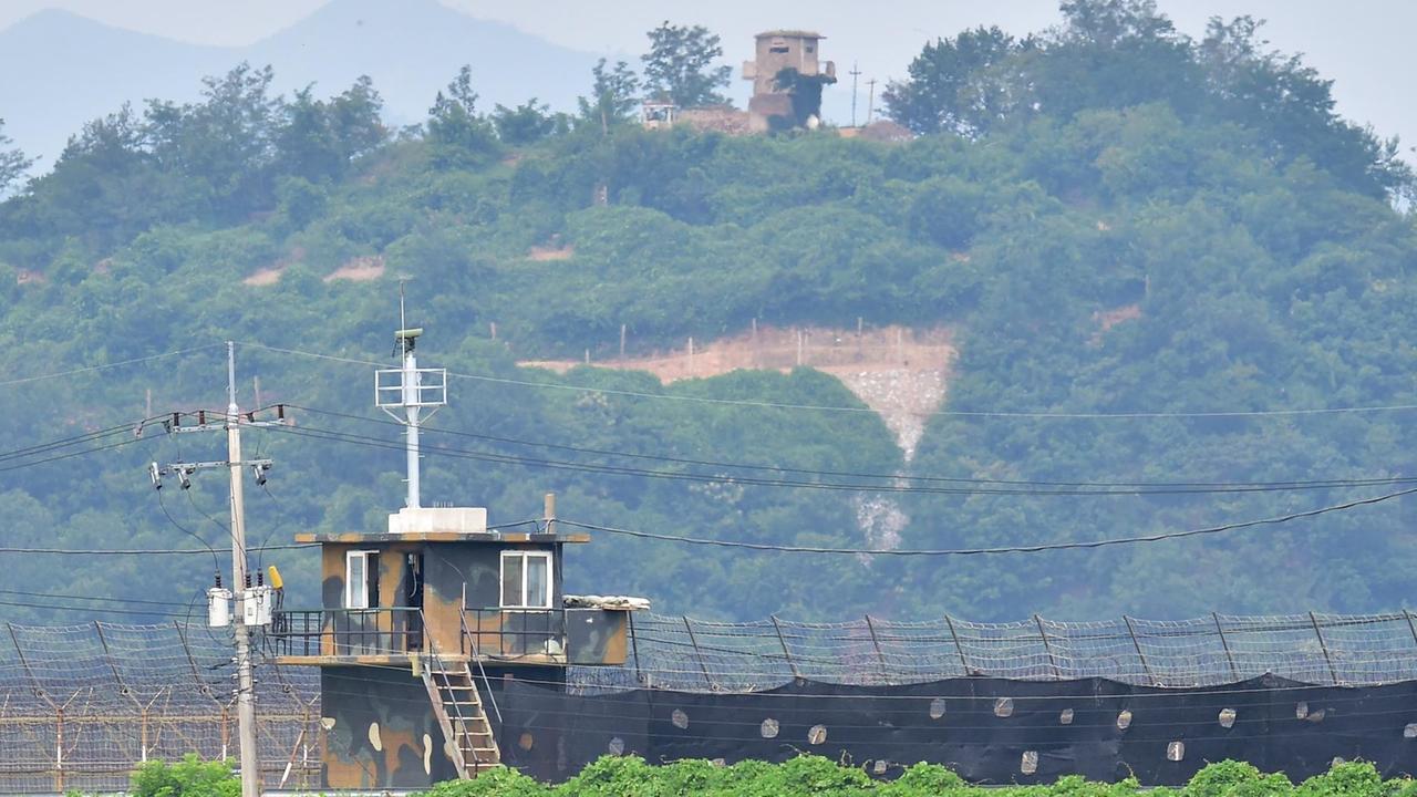Der nordkoreanische Grenzposten im Hintergrund befindet sich auf einem grün bewachsenen Hügel. Der nordkoreanische Grenzposten im Hintergrund befindet sich auf einem grün bewachsenen Hügel.