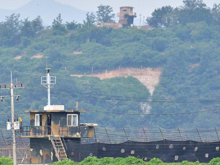 Der nordkoreanische Grenzposten im Hintergrund befindet sich auf einem grün bewachsenen Hügel.