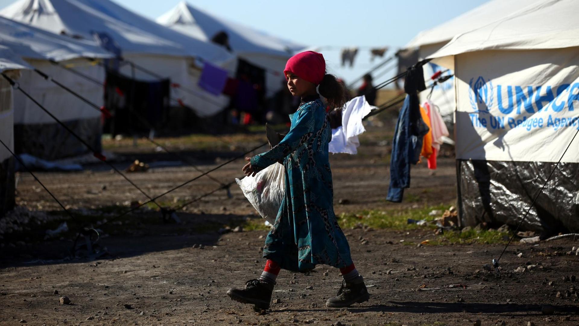 Ein Flüchtlingsmädchen mit Plastiktüte geht durch ein UN-Camp in Syrien.