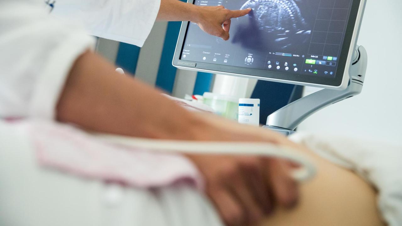 Ein Arzt untersucht eine schwangere Frau mit Ultraschall Ein Arzt untersucht eine schwangere Frau mit Ultraschall