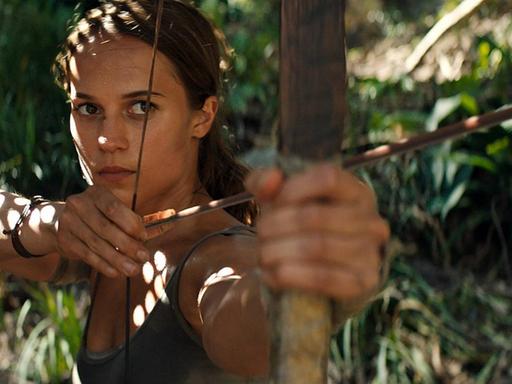 Alicia Vikander als Lara Croft in "Tomb Raider", sie ist von vorne zu sehen, schaut konzentriert und spannt einen Bogen