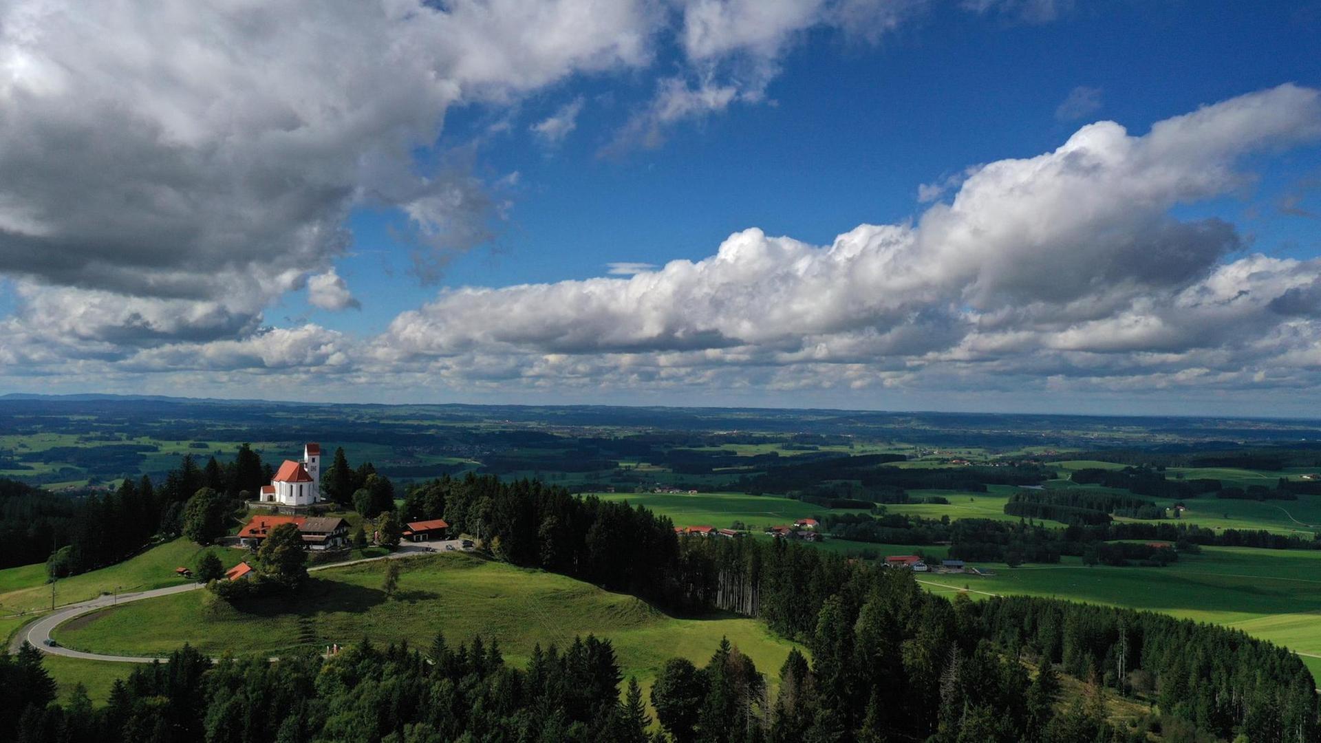 Wechselnd bewölkt zeigt sich der Himmel über der Kirche Sankt Georg auf dem 1055 Meter hohen Auerberg (Luftaufnahme mit einer Drohne).