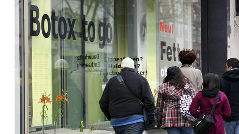Passanten vor dem Schaufenster einer Schönheitspraxis in Berlin, die Botox-to-go und Fett-weg-Behandlung anbietet