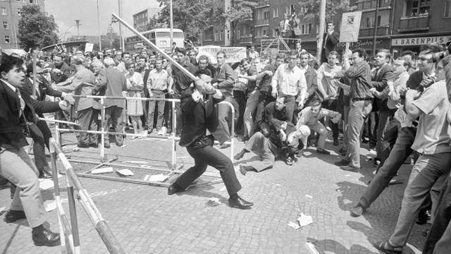 Beim Staatsbesuch des persischen Schah demonstrieren Berliner Studenten 1967 gegen das repressive Regime des Herrschers. Vor dem Rathaus in Schöneberg kommt es am 2. Juni zu Ausschreitungen zwischen Demonstranten, Schah-Anhängern und der Polizei.