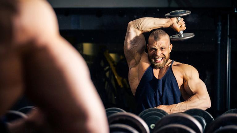 Ein Bodybuilder betrachtet sich im Spiegel. Ein Bodybuilder betrachtet sich im Spiegel.