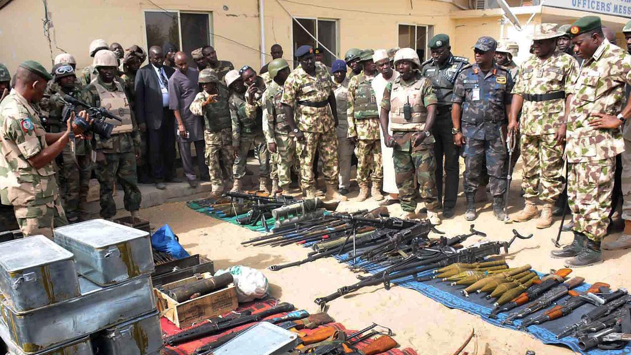 Goodluck Jonathan schaut auf eine Reihe von auf den Boden gelegten Waffen unterschiedlicher Art.
