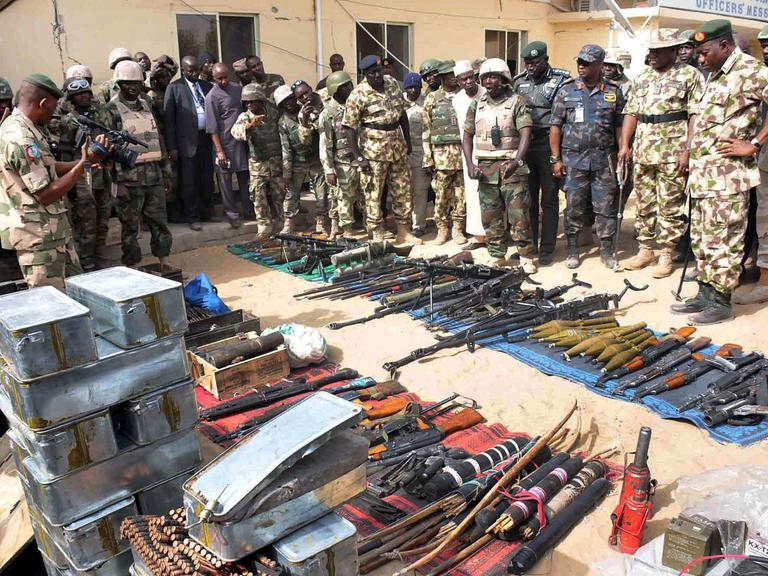 Goodluck Jonathan schaut auf eine Reihe von auf den Boden gelegten Waffen unterschiedlicher Art.