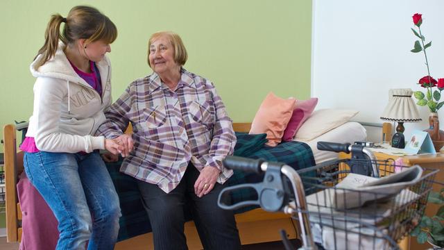 Eine Pflegerin kümmert sich in einem Heim um eine Seniorin.