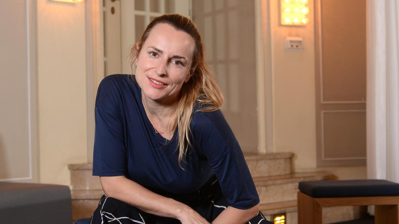 Anna Bergmann, Schauspieldirektorin des Badischen Staatstheaters. Sie sitzt im Theaterfoyer auf einem Hocker und schaut direkt in die Kamera. Foto: Mike Wolff | Verwendung weltweit Anna Bergmann, Schauspieldirektorin des Badischen Staatstheaters. Sie sitzt im Theaterfoyer auf einem Hocker und schaut direkt in die Kamera. Foto: Mike Wolff | Verwendung weltweit