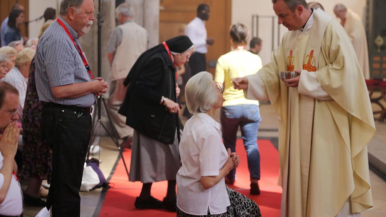 Gläubige nehmen am 07.06.2013 in Köln (Nordrhein-Westfalen) an einer Eucharistiefeier teil. Der Priester legt einer knienden Dame eine Hostie auf ihre Zunge Gläubige nehmen am 07.06.2013 in Köln (Nordrhein-Westfalen) an einer Eucharistiefeier teil. Der Priester legt einer knienden Dame eine Hostie auf ihre Zunge