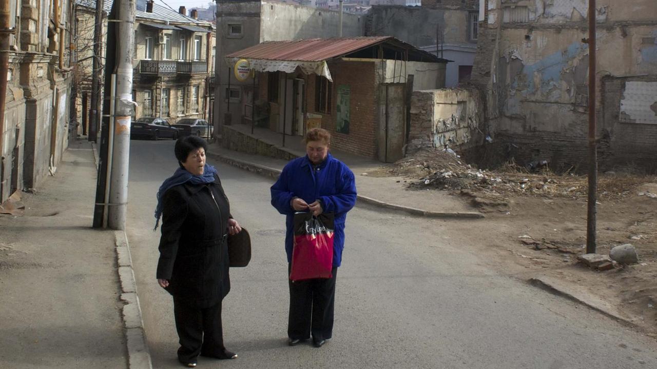 Zwei Frauen in Tiflis mit Einkaufstaschen auf einer etwas heruntergekommenen Straße