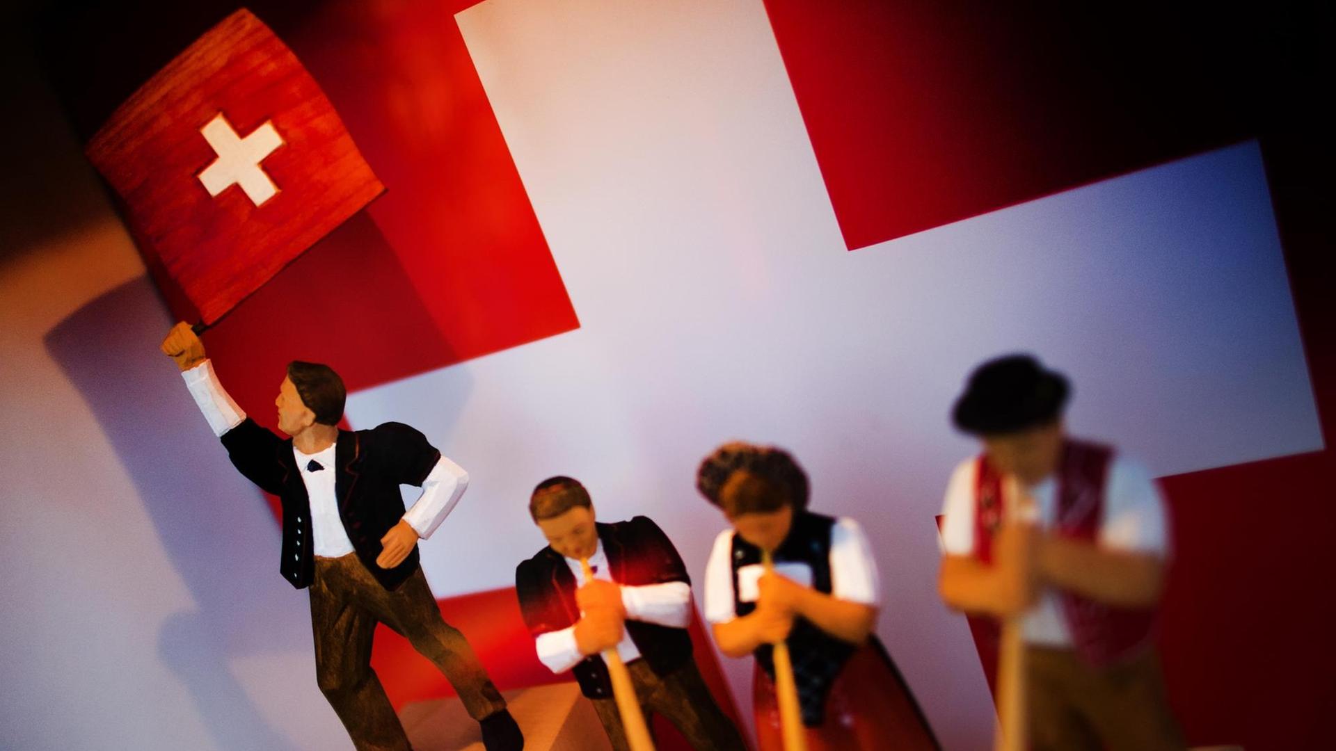 An einem Infostand des Partnerlandes Schweiz auf der Leipziger Buchmesse in Leipzig (Sachsen) stehen am 12.03.2014 Holzschnitzfiguren in einer Glasvitrine. Vom 13. bis 16. März präsentieren sich auf der Messe 2000 Verlage mit ihren Neuerscheinungen. Foto: Arno Burgi/dpa An einem Infostand des Partnerlandes Schweiz auf der Leipziger Buchmesse in Leipzig (Sachsen) stehen am 12.03.2014 Holzschnitzfiguren in einer Glasvitrine. Vom 13. bis 16. März präsentieren sich auf der Messe 2000 Verlage mit ihren Neuerscheinungen. Foto: Arno Burgi/dpa