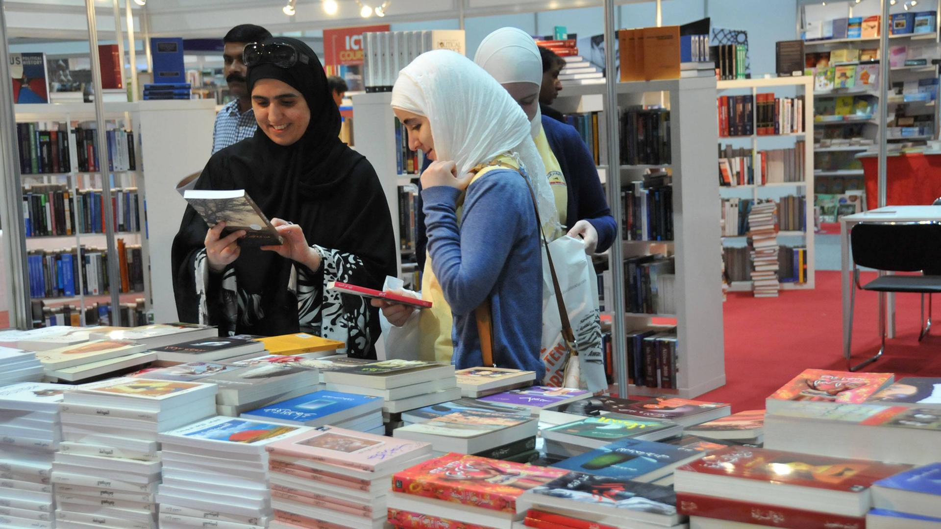 Auf der internationalen Buchmesse in Abu Dhabi gucken sich zwei Frauen Bücher an. Auf der internationalen Buchmesse in Abu Dhabi gucken sich zwei Frauen Bücher an.