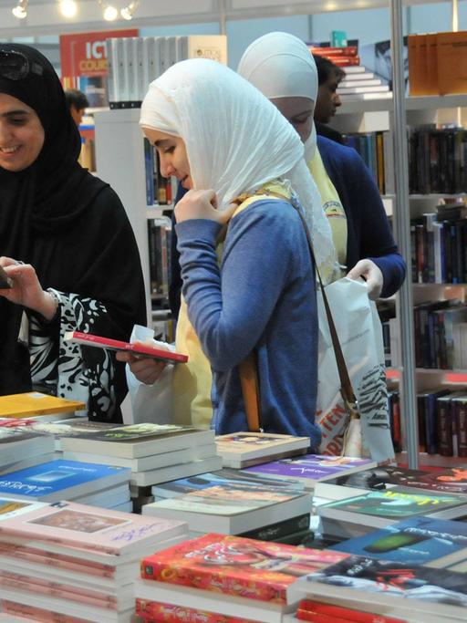 Auf der internationalen Buchmesse in Abu Dhabi gucken sich zwei Frauen Bücher an.