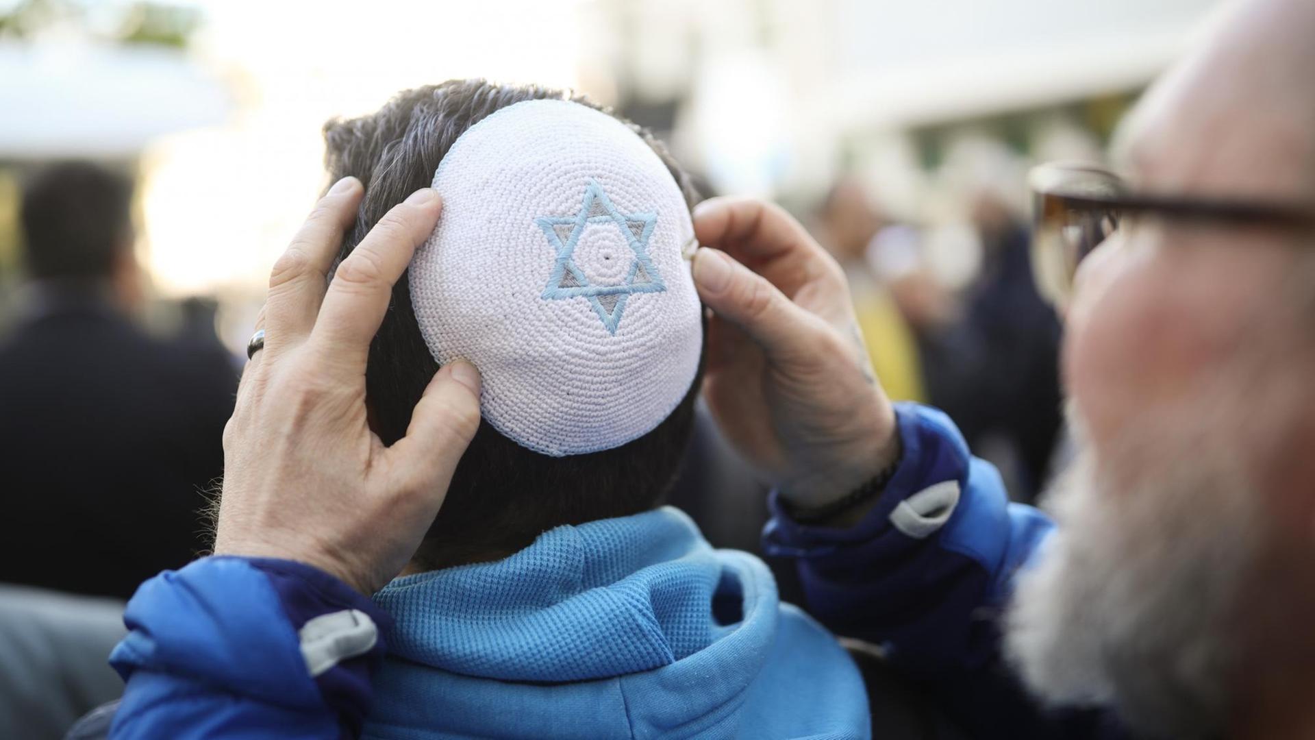 Ein Mann hilft einem weiteren auf der Solidaritätskundgebung "Berlin trägt Kippa" der Jüdischen Gemeinde zu Berlin seine Kippa aufzusetzen. Ein Mann hilft einem weiteren auf der Solidaritätskundgebung "Berlin trägt Kippa" der Jüdischen Gemeinde zu Berlin seine Kippa aufzusetzen.
