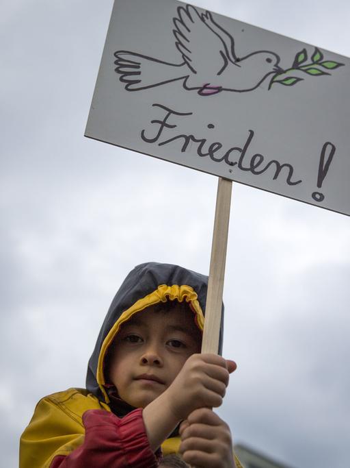 Ein Kind trägt am Potsdamer Platz in Berlin ein Plakat mit einer Friedenstaube