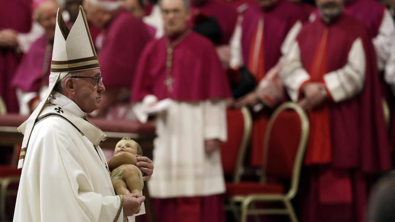 Papst Franziskus hält während der Heiligabend-Messe im Petersdom eine Figur des Jesuskindes. Papst Franziskus hält während der Heiligabend-Messe im Petersdom eine Figur des Jesuskindes.