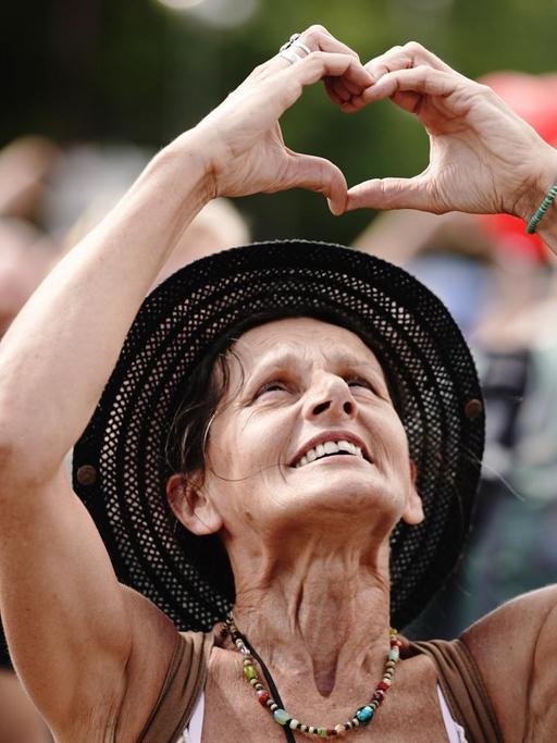 Eine Teilnehmerin formt ein Herz mit den Händen bei einer Demonstration gegen die Corona-Maßnahmen.
