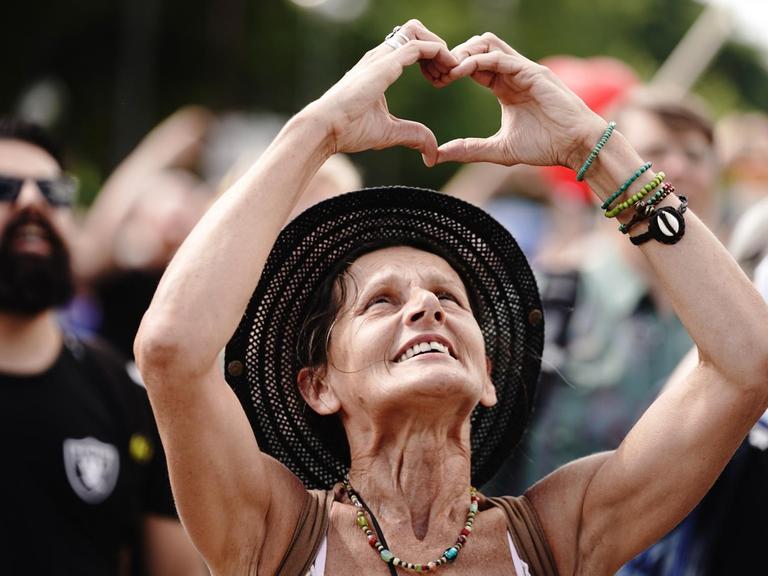 Eine Teilnehmerin formt ein Herz mit den Händen bei einer Demonstration gegen die Corona-Maßnahmen.